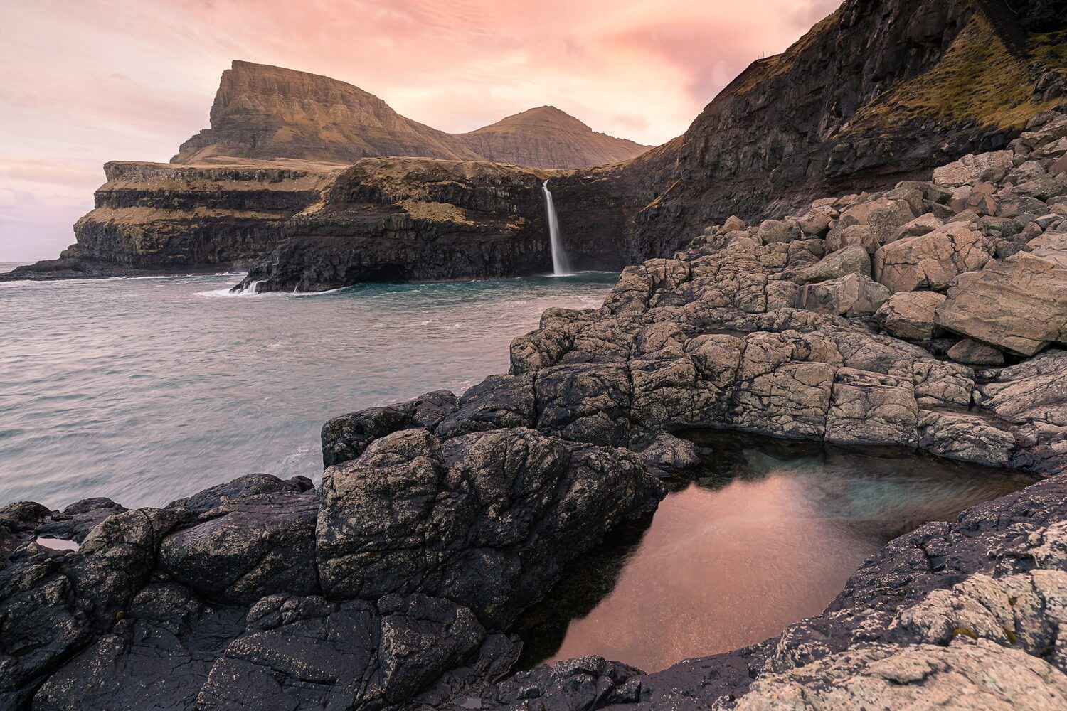 Budir beach in Iceland, in pink sunset, view of the sea and the rocky cliffs.