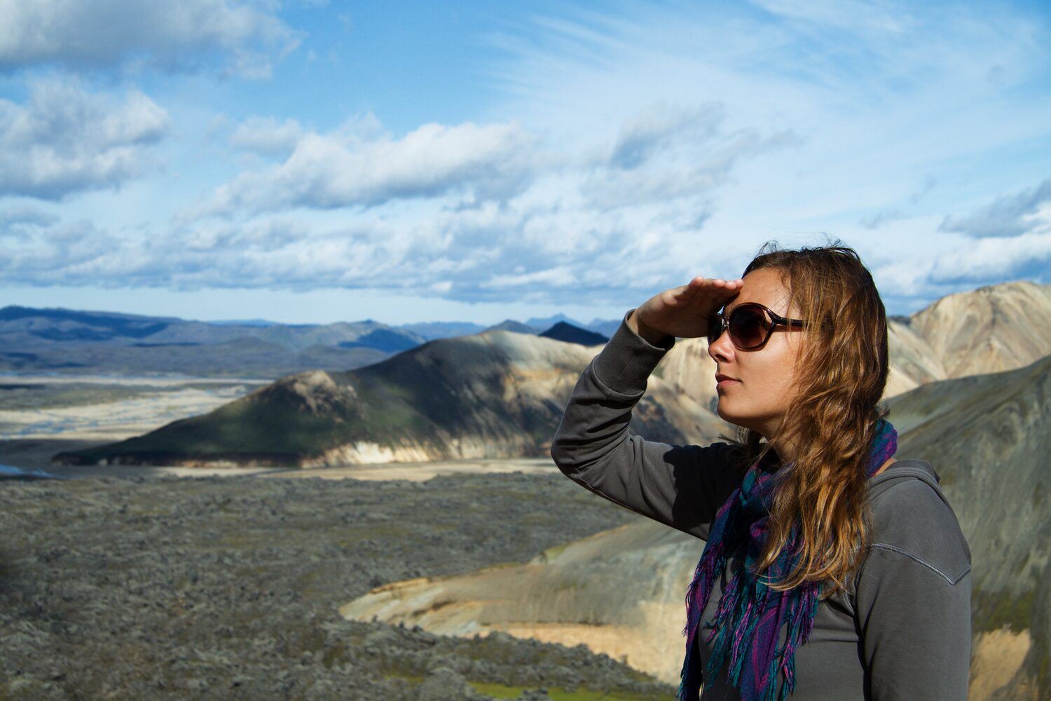Female tourist with sunglasses, looking out at scenic view in Landmannalaugar, Iceland.