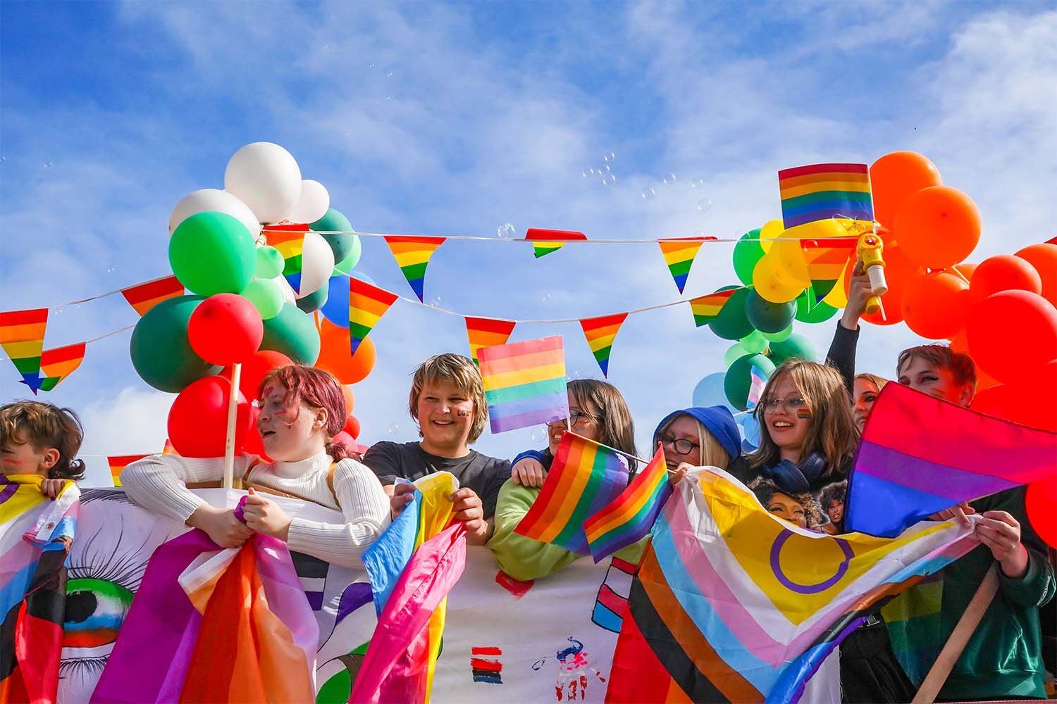 Cheering crowd of children in multicolors with pride flags celebrating Reykjavik pride in Iceland.