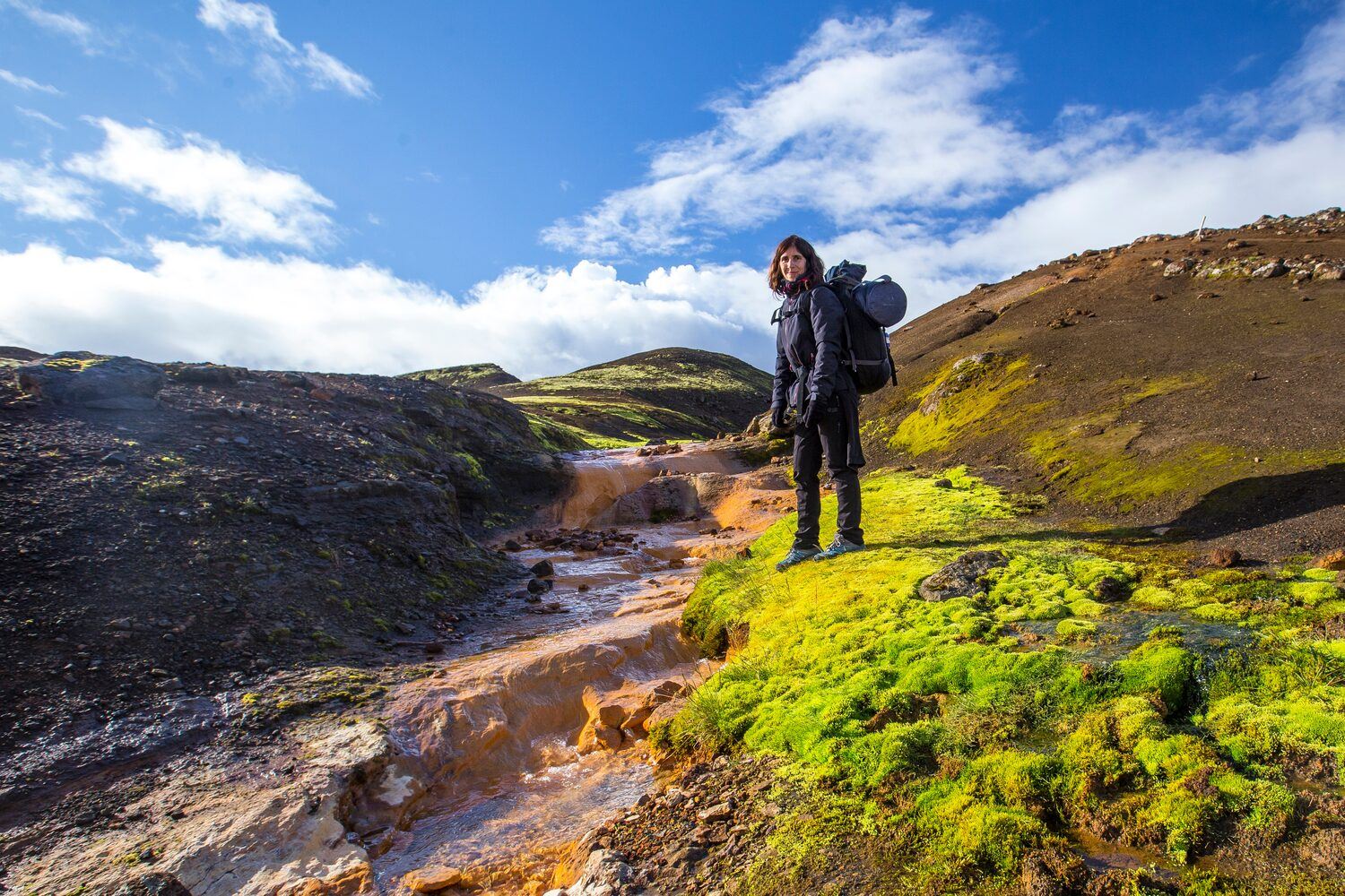 Woman in outdoor gear with backpack on hiking trail in Landmannalaugar, Iceland.