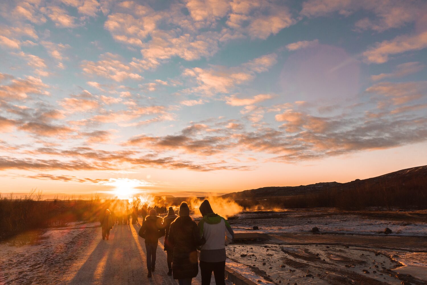 Tourists walking close to Geysir in Iceland in summer evening sunset.