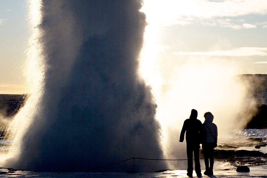 Couple standing by erupted geyser in Iceland