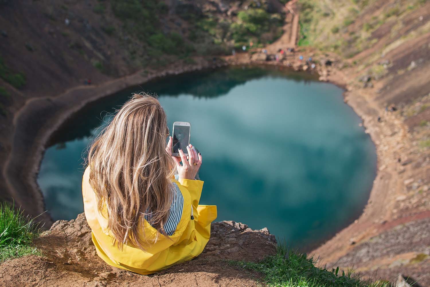 Woman taking photos of volcanic crater from above