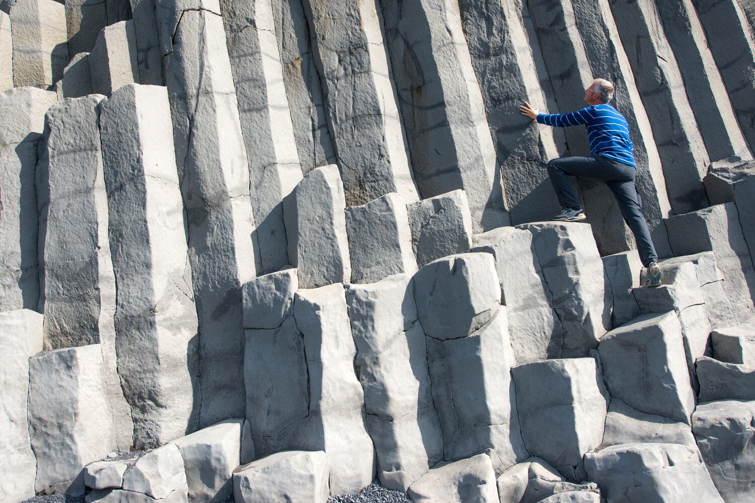Man climbing on basalt cliff in Iceland
