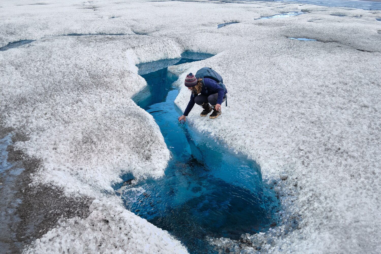 Woman by glacier river in ice crevasse