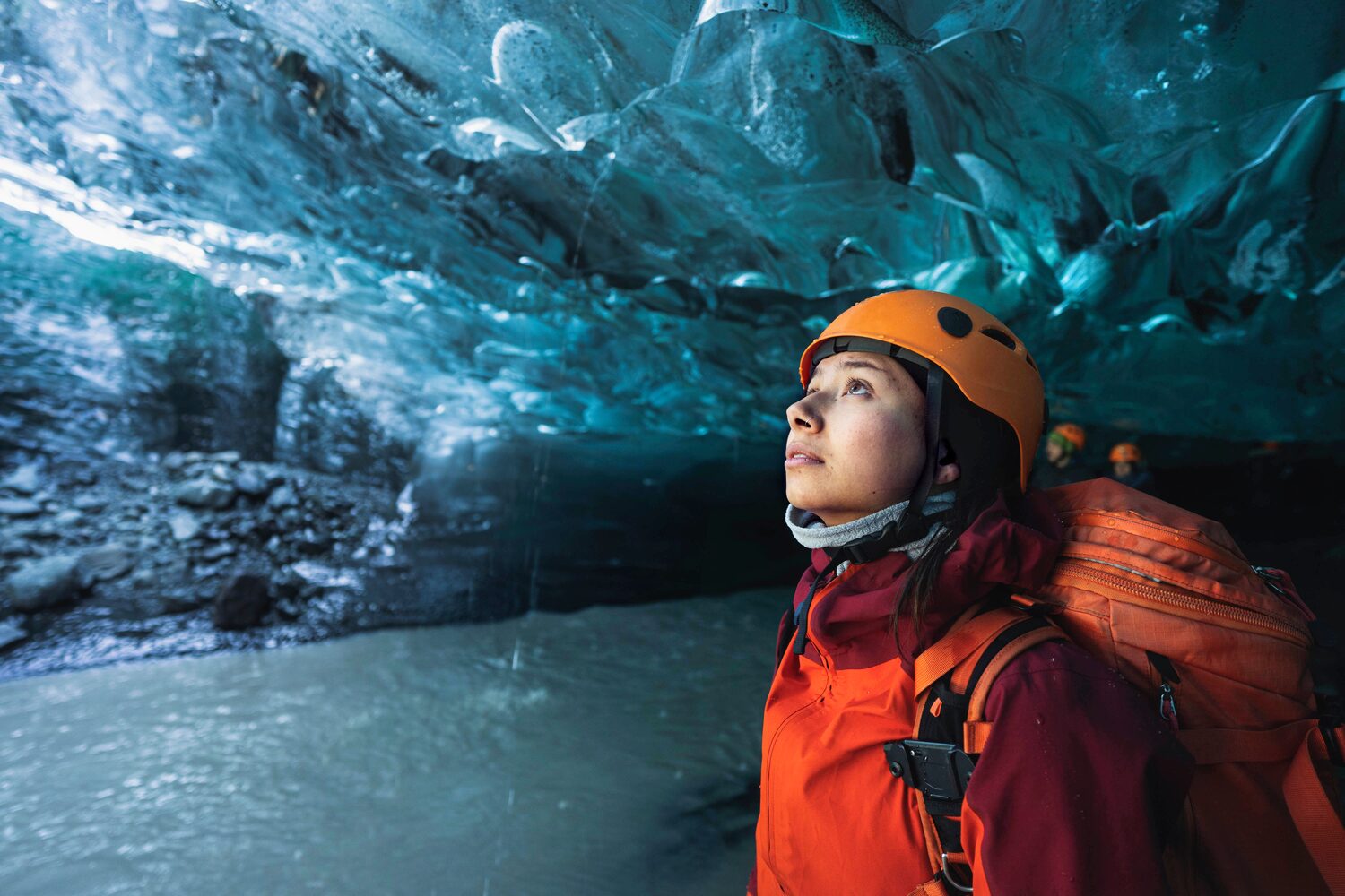 Woman with red jacket and helmet in ice cave