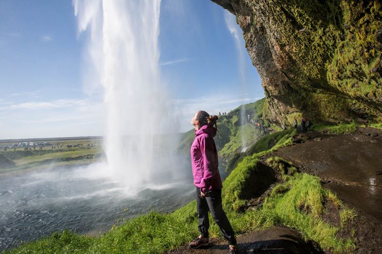 Woman wearing pink jacket by waterfall in Iceland