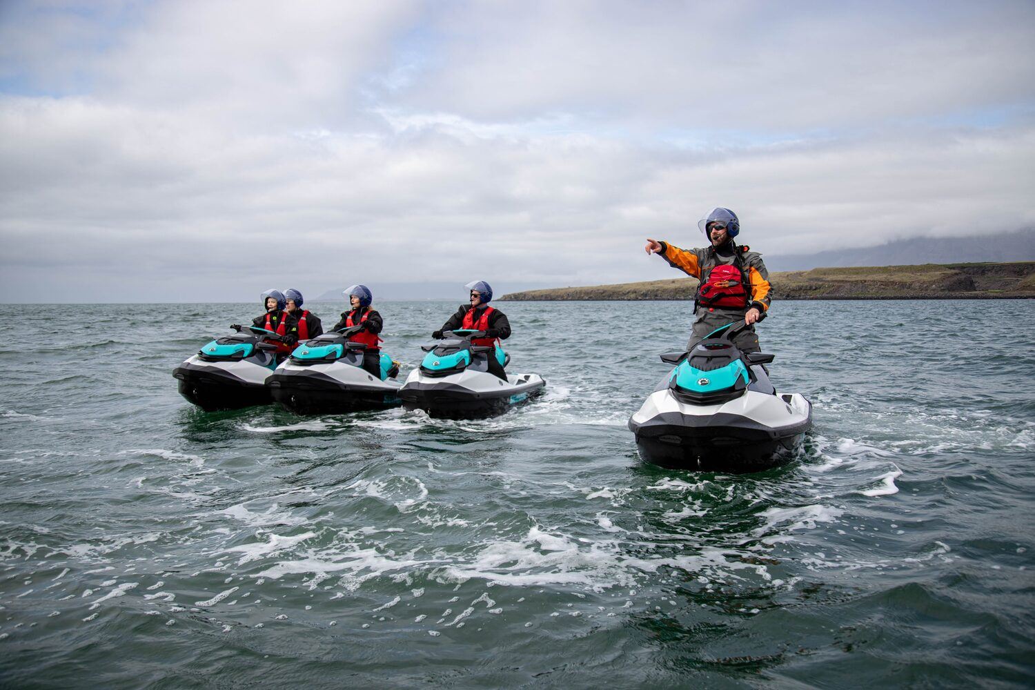 Group of tourists  in a line on jet skiing tour in Iceland in the sea with cloudy sky 
