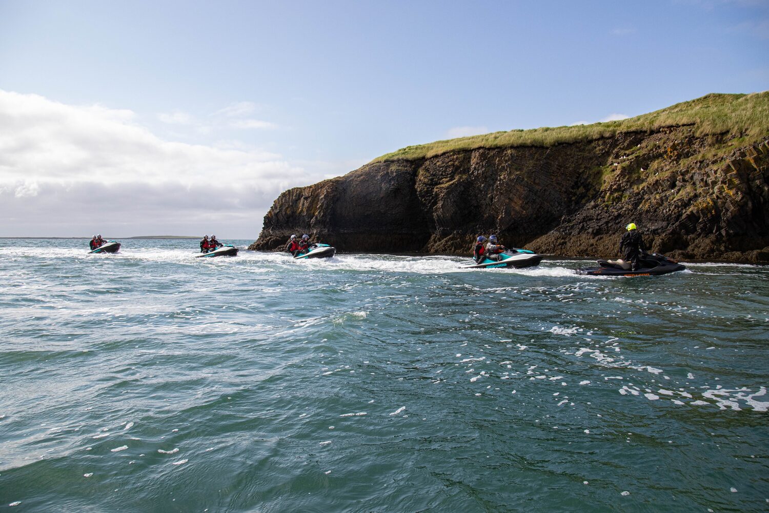 Jet Ski tour group in distance in the sea in the foreground cliff edge