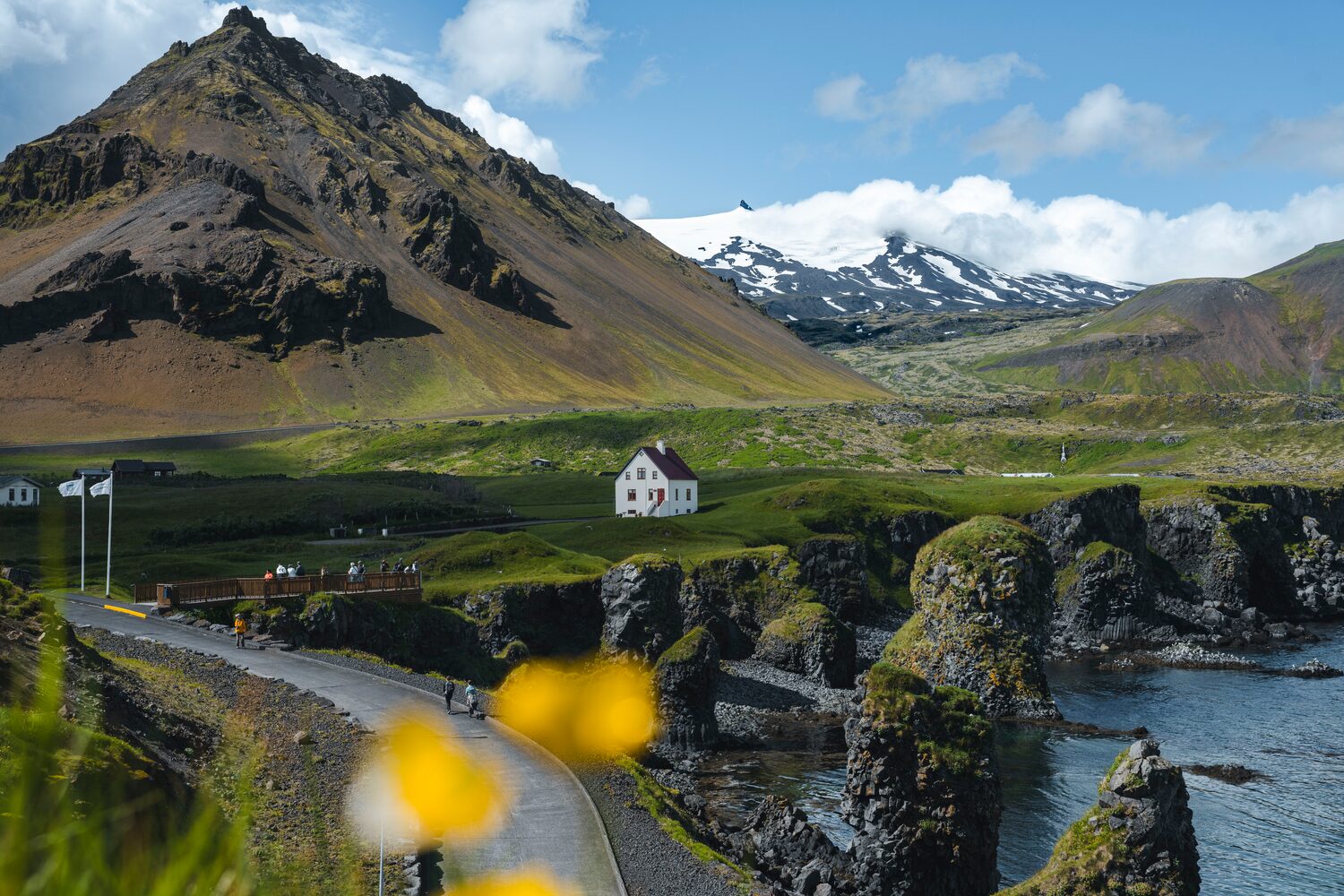 View of a solo white house in the village of Arnarstapi, surrounded by nature and mountains