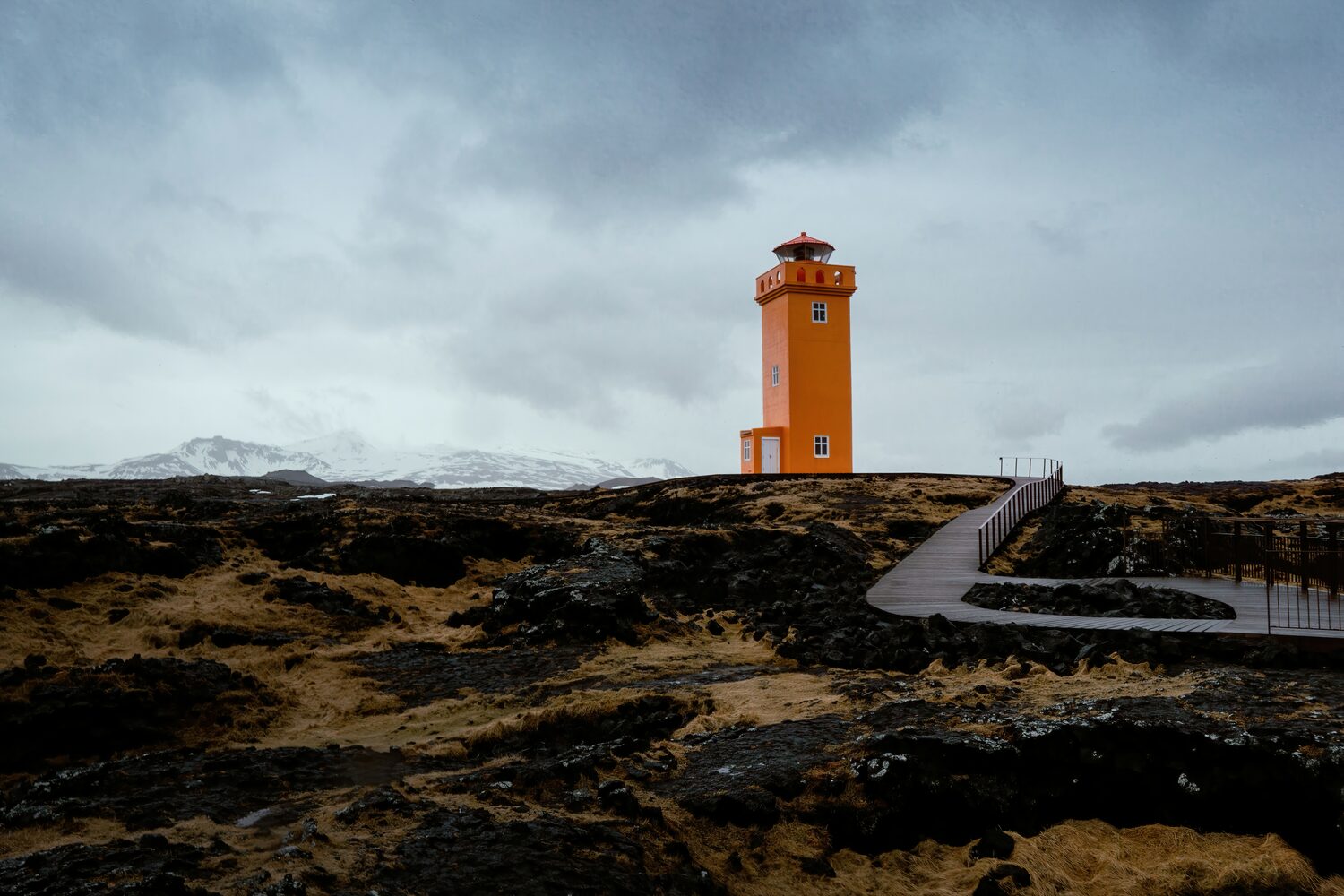 Beautiful bright orange lighthouse with curved wooden footpath