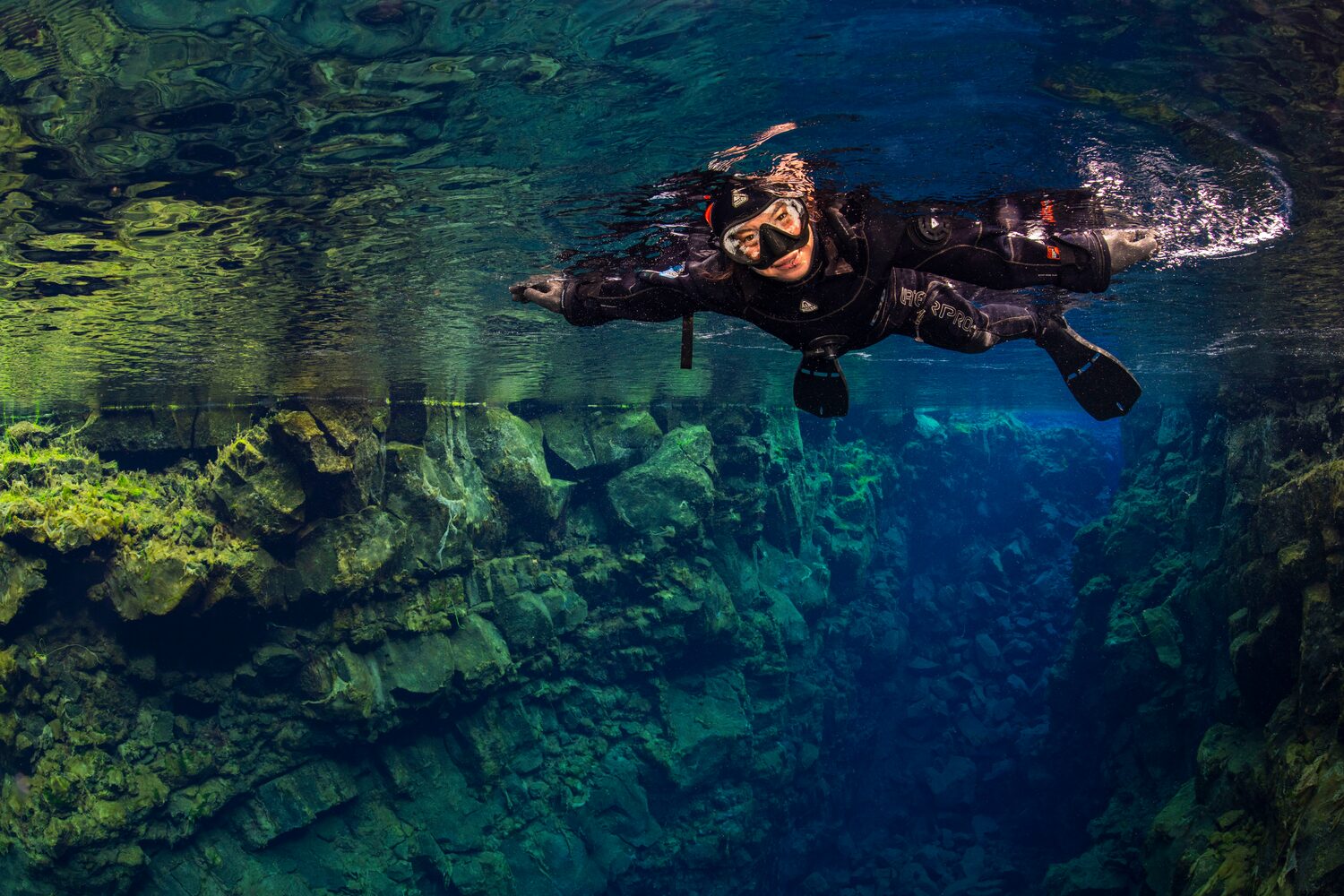 Woman with snorkeling gear swimming in Silfra Fissure
