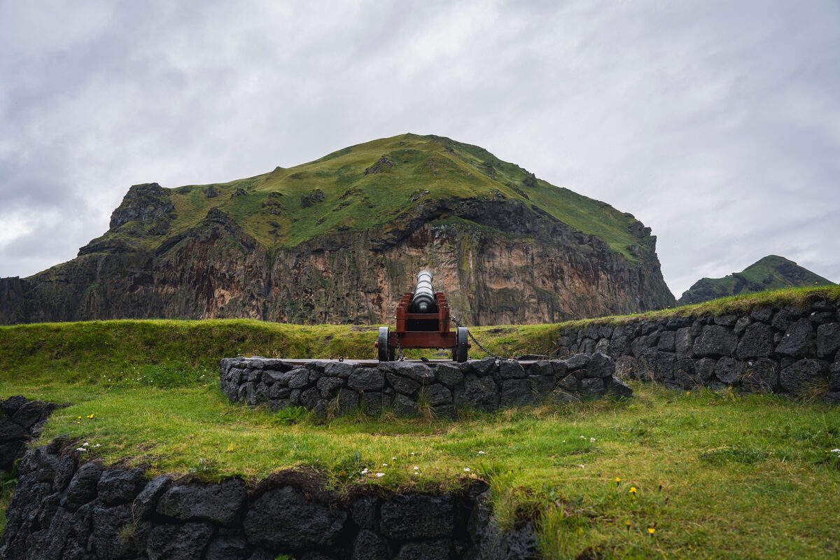 Old canon by mountains in Vestmannaeyjar