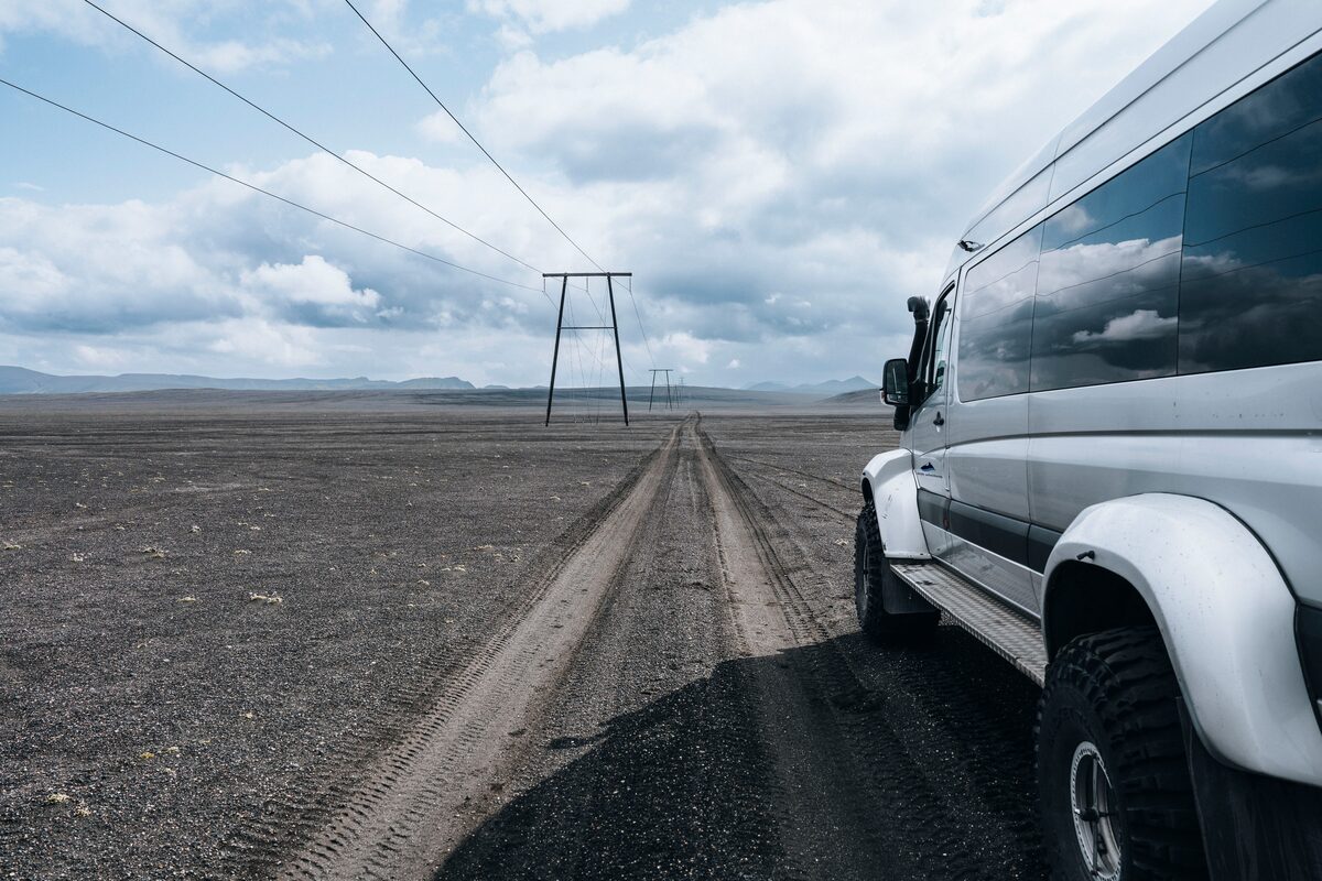 Side of white Mercedes super jeep driving through Iceland terrain 