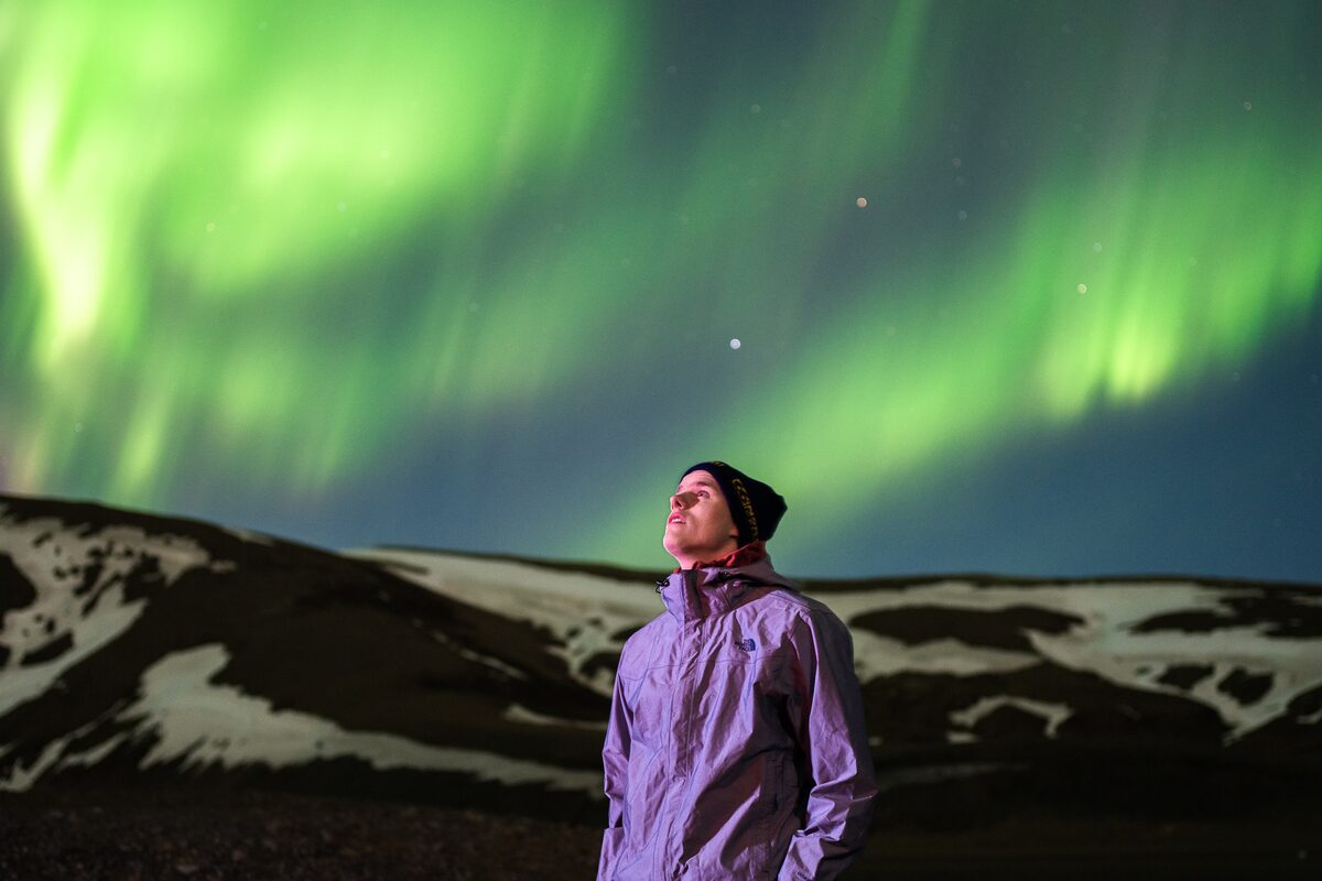 Man looking to sky with northern lights