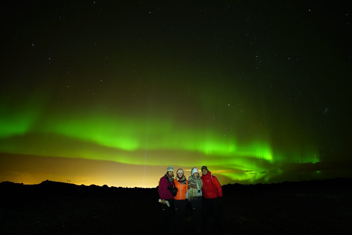 Group of people posing for photo under aurora