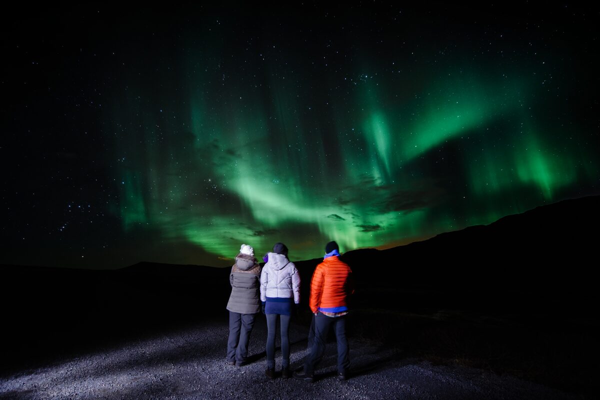 Three people watching aurora in Iceland