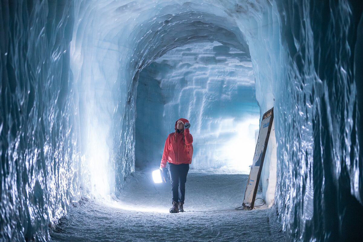 Woman with red jacket walking in ice tunnel