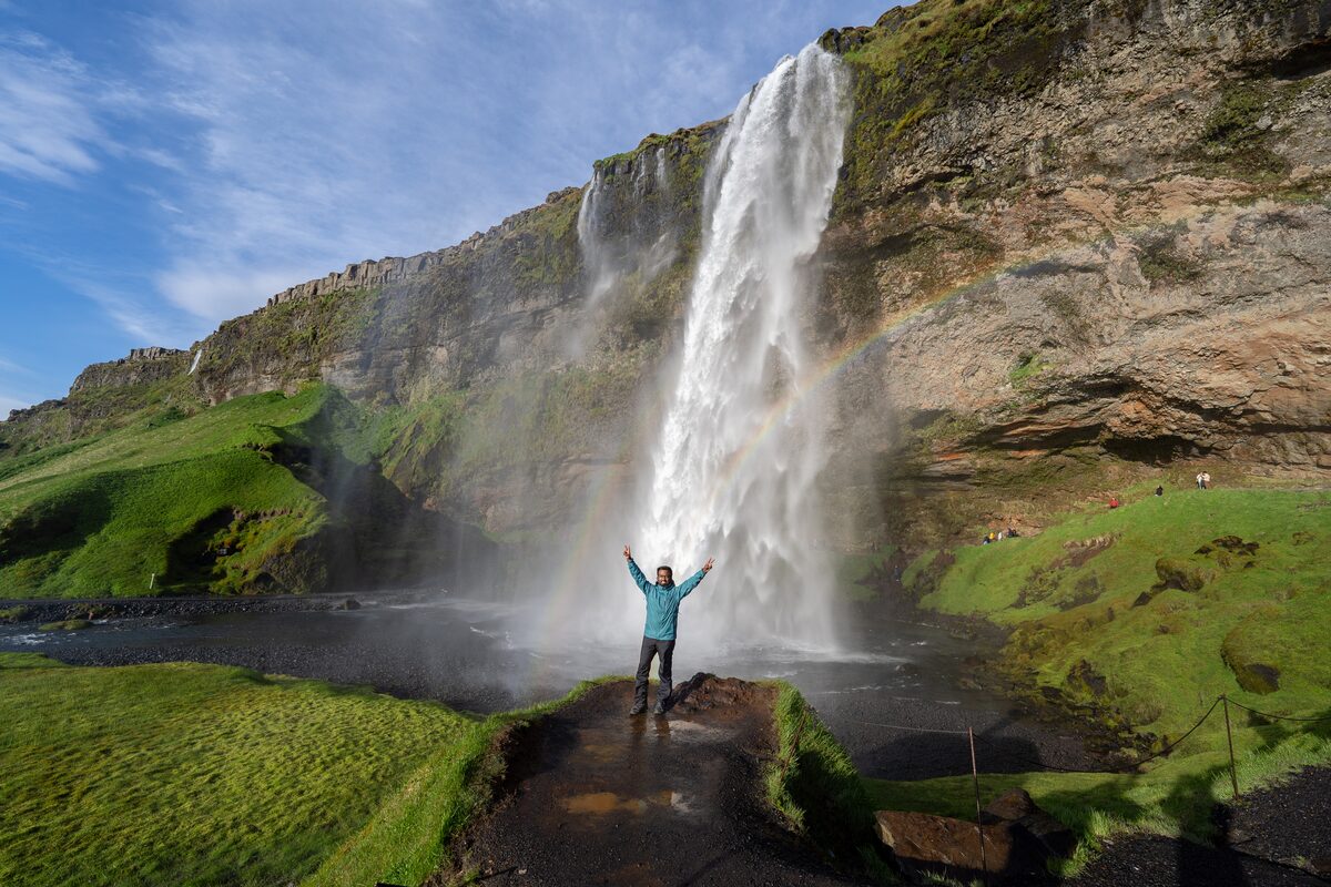 Happy man standing by waterfall in Iceland