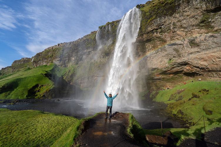 Happy man standing by waterfall in Iceland