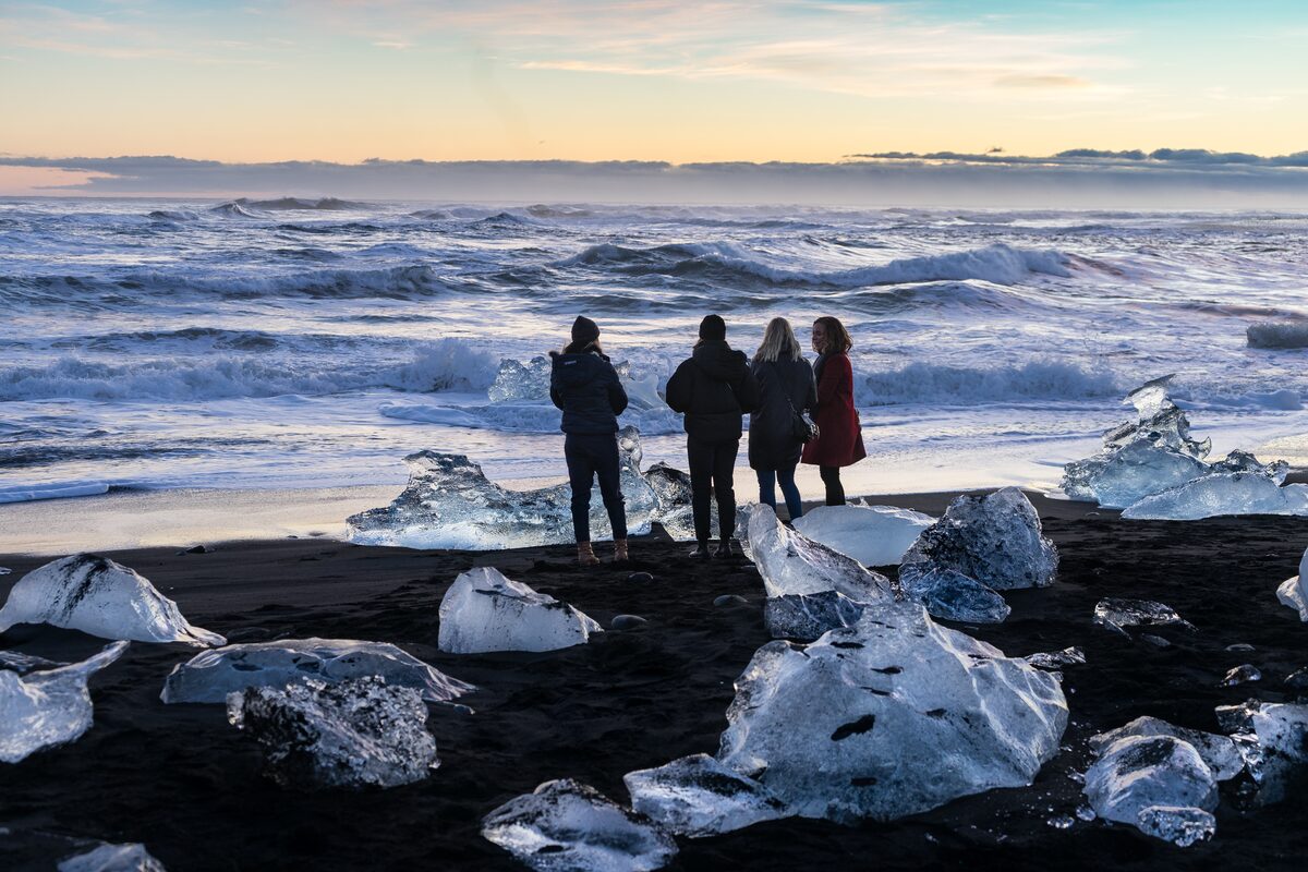 Group of people by sea shore full of small icebergs