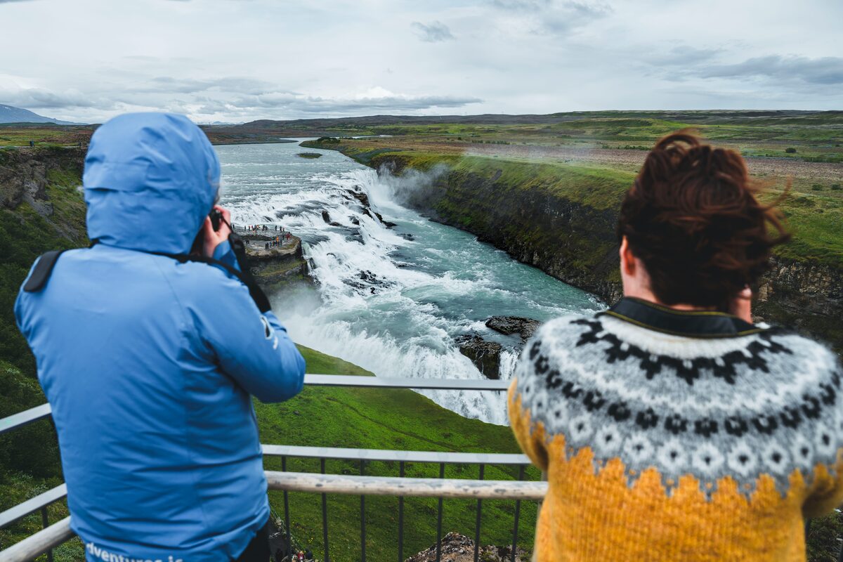 Woman and man taking photos of waterfall in Iceland