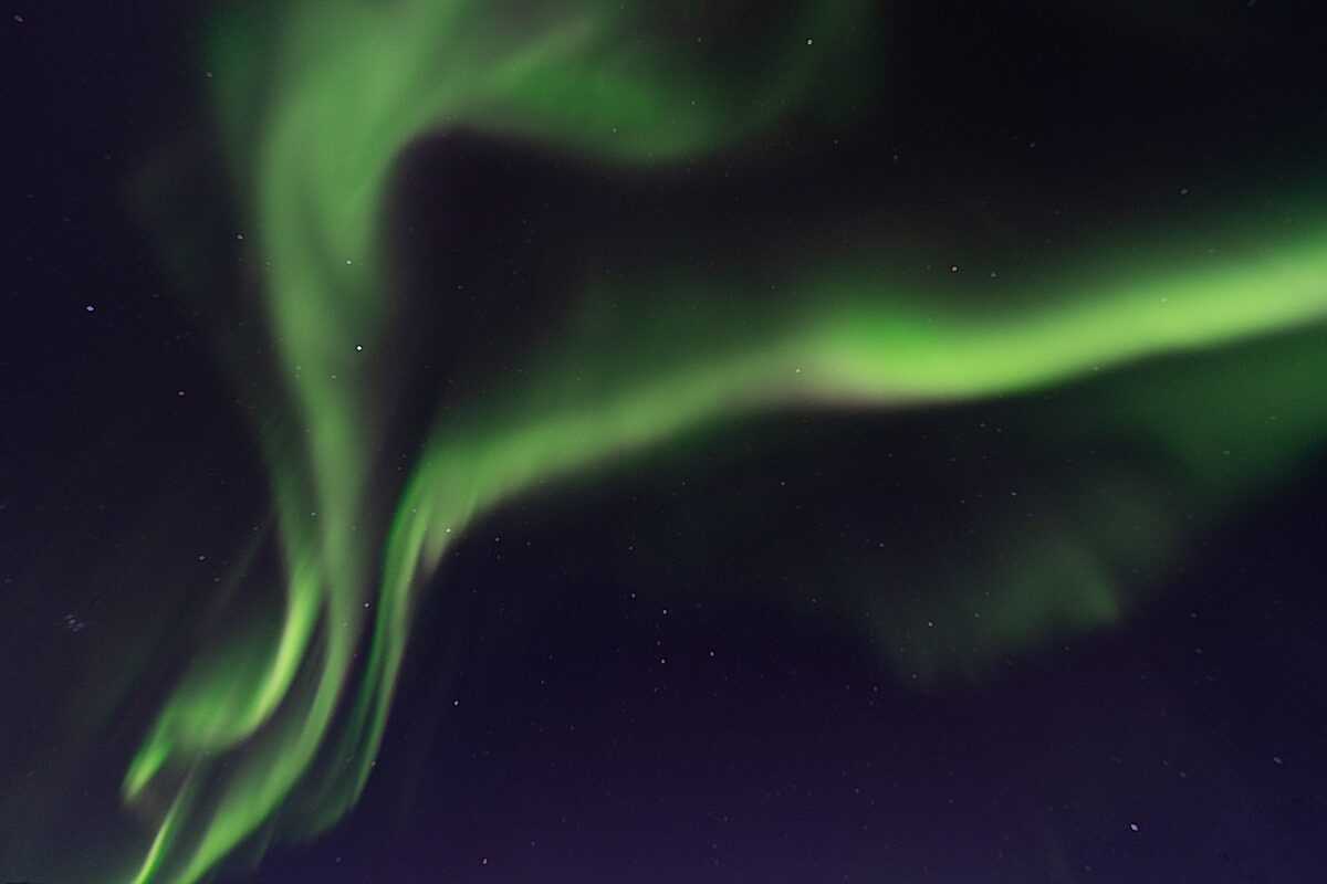 Iceland dark night sky with green aurora borealis.