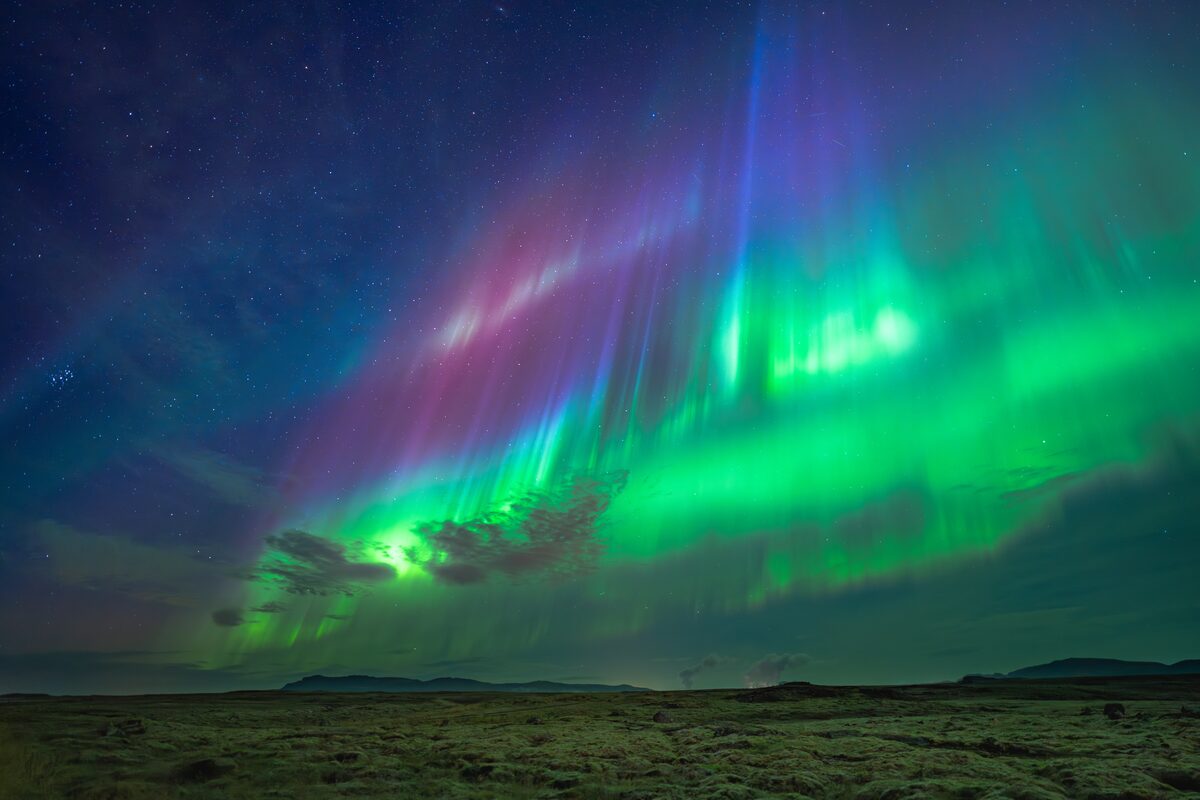 Green and purple northern lights in sky.