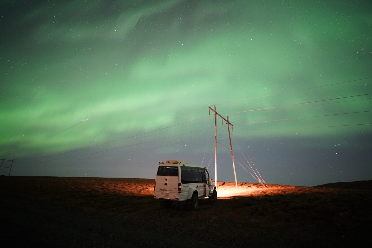 Northern lights above white tour bus.