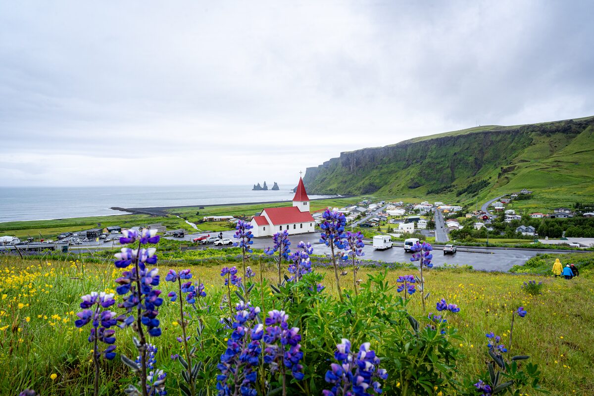 Sprin gview of Vik Church with spring flowers and green fields surrounding the town