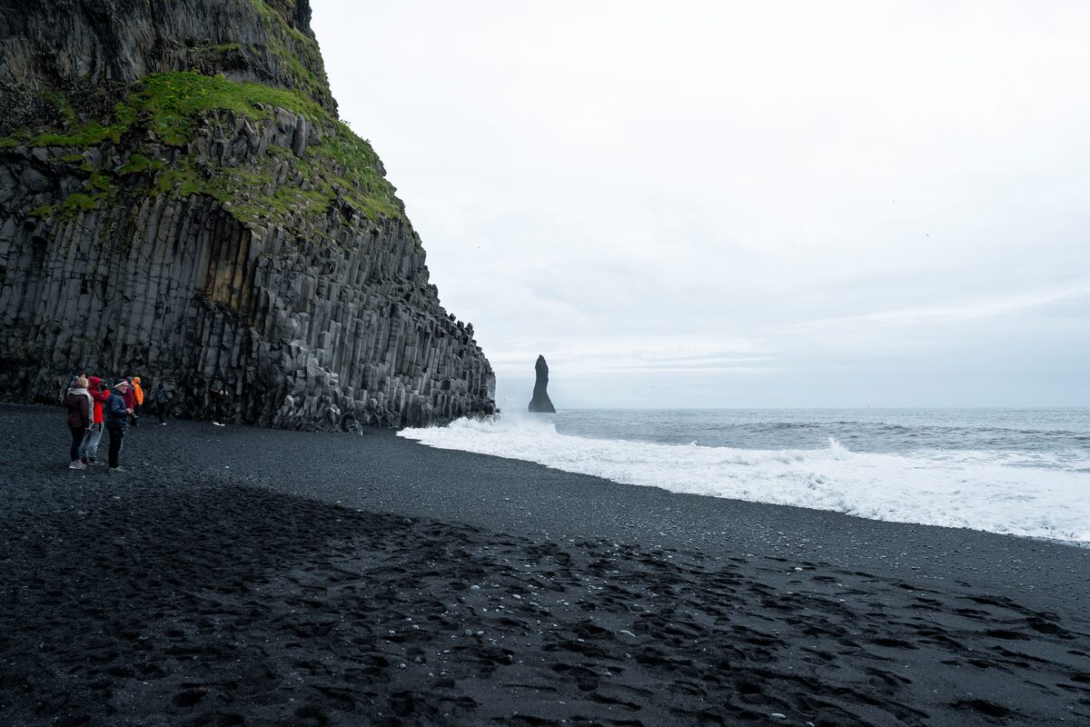 Group of tourists standing in a volcanic Reynisfjara black sand beach