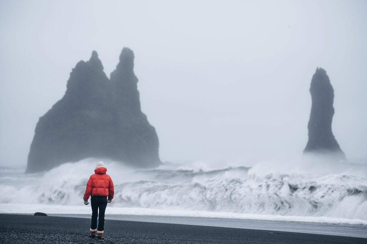 Woman with red jacket in windy beach