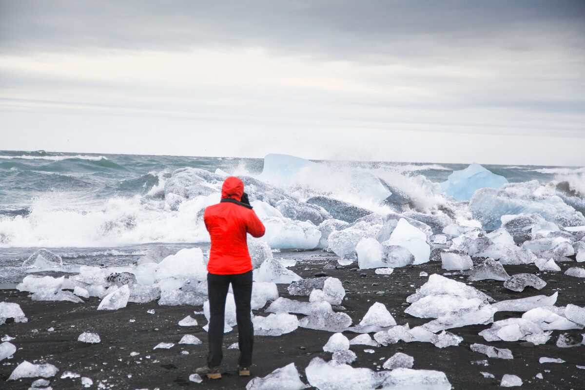 Woman with red jacket taking photos in beach