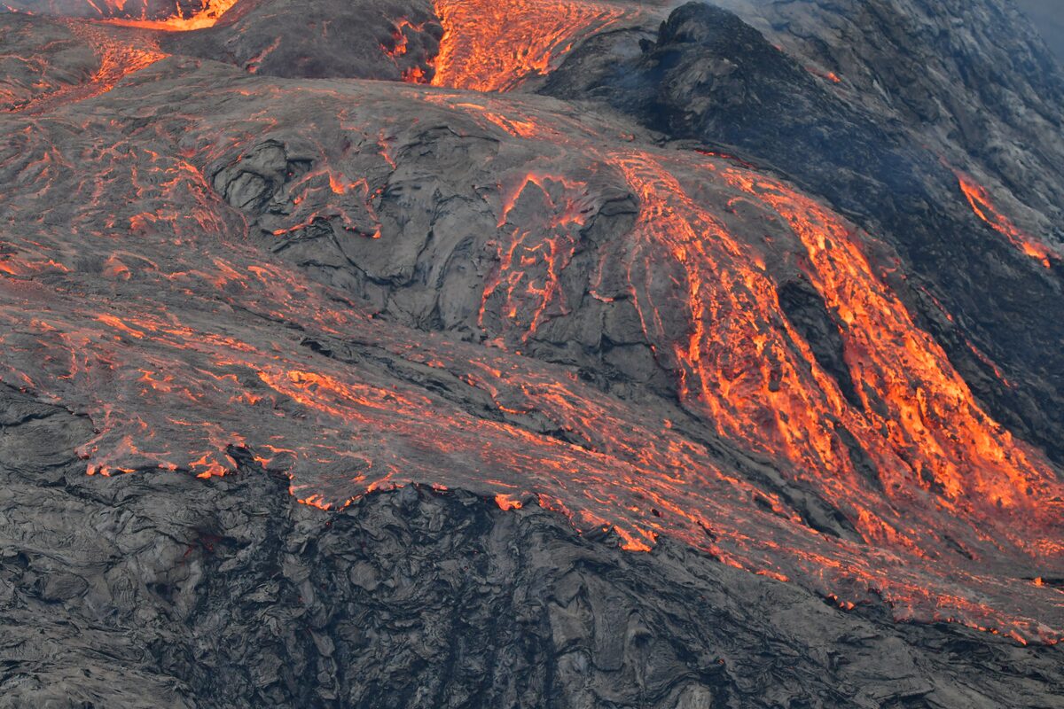Molten lava flowing through dark volcanic rock during an Icelandic volcanic eruption.