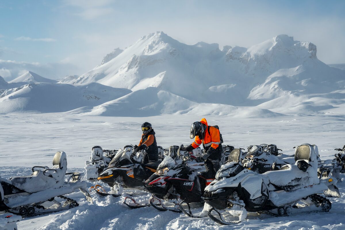 People on snowmobiles by the mountains
