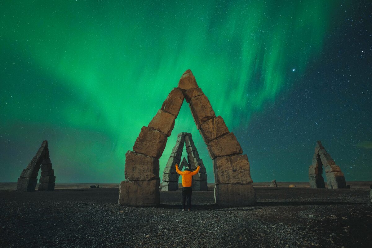 Beautiful stone henge in Iceland during viv green northern lights at night