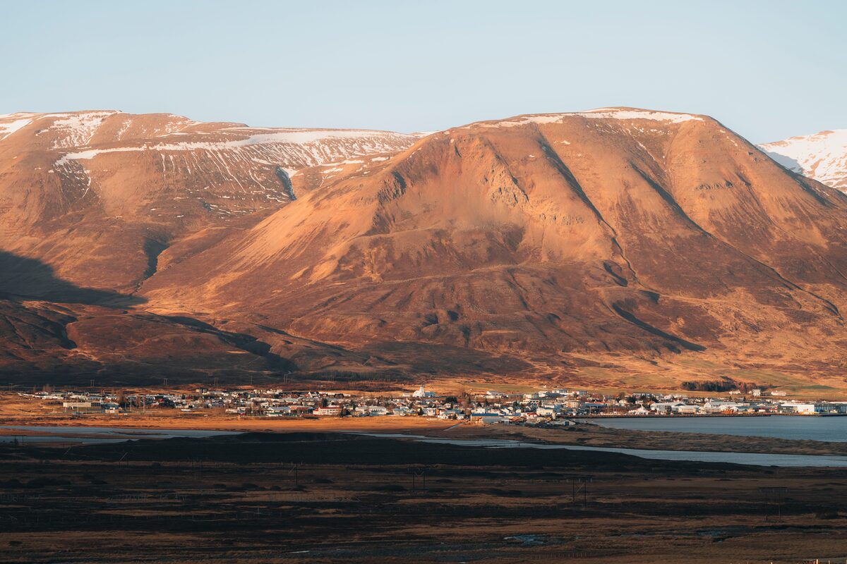 Wide view of small fishing village Dalvik in front of snow covered mountain 