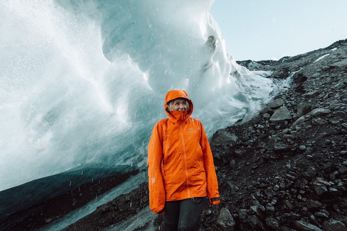 Woman in orange jacket standing in the rain in the area of the glacier