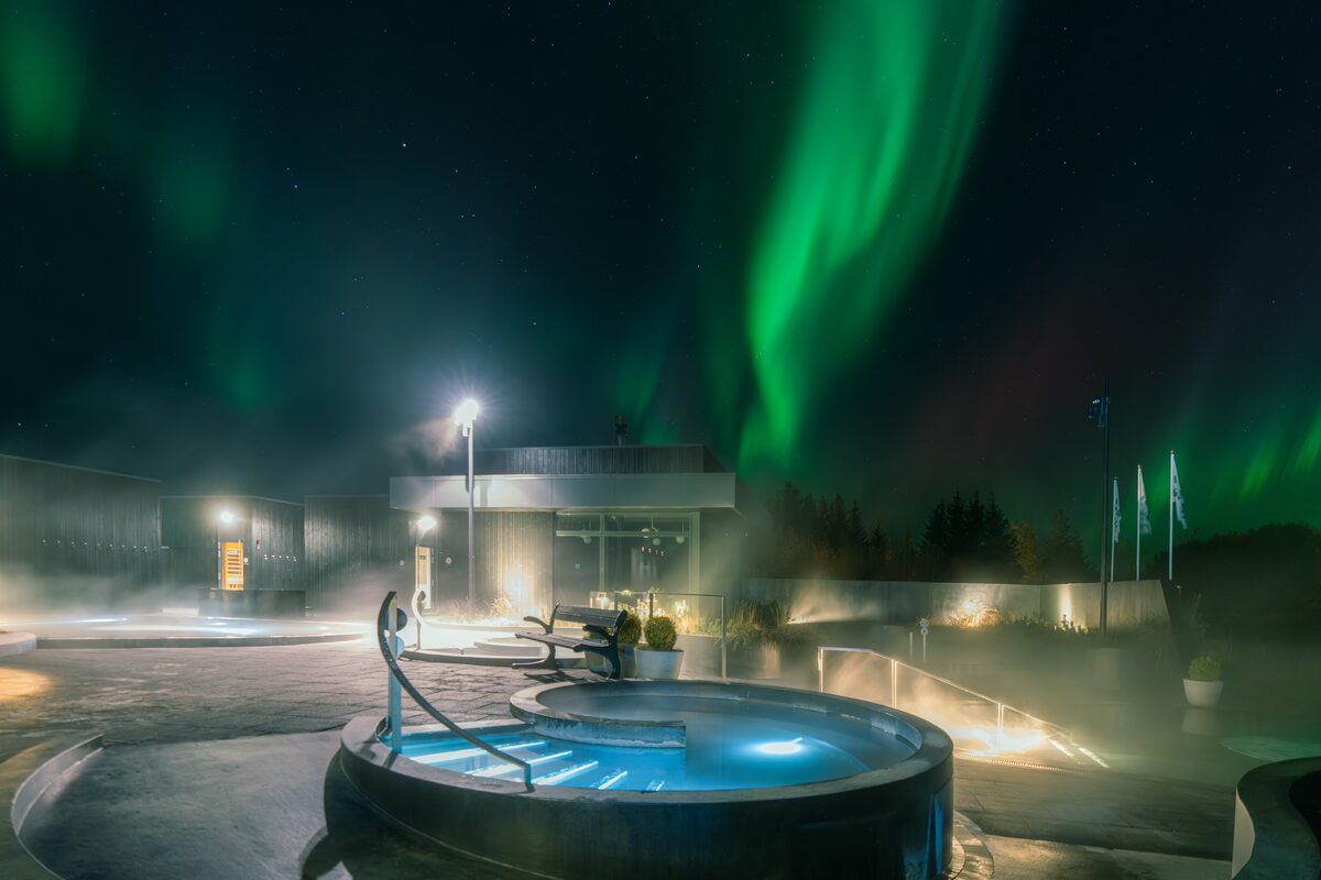 Northern lights shining bright over krauma geothermal small pool at night 