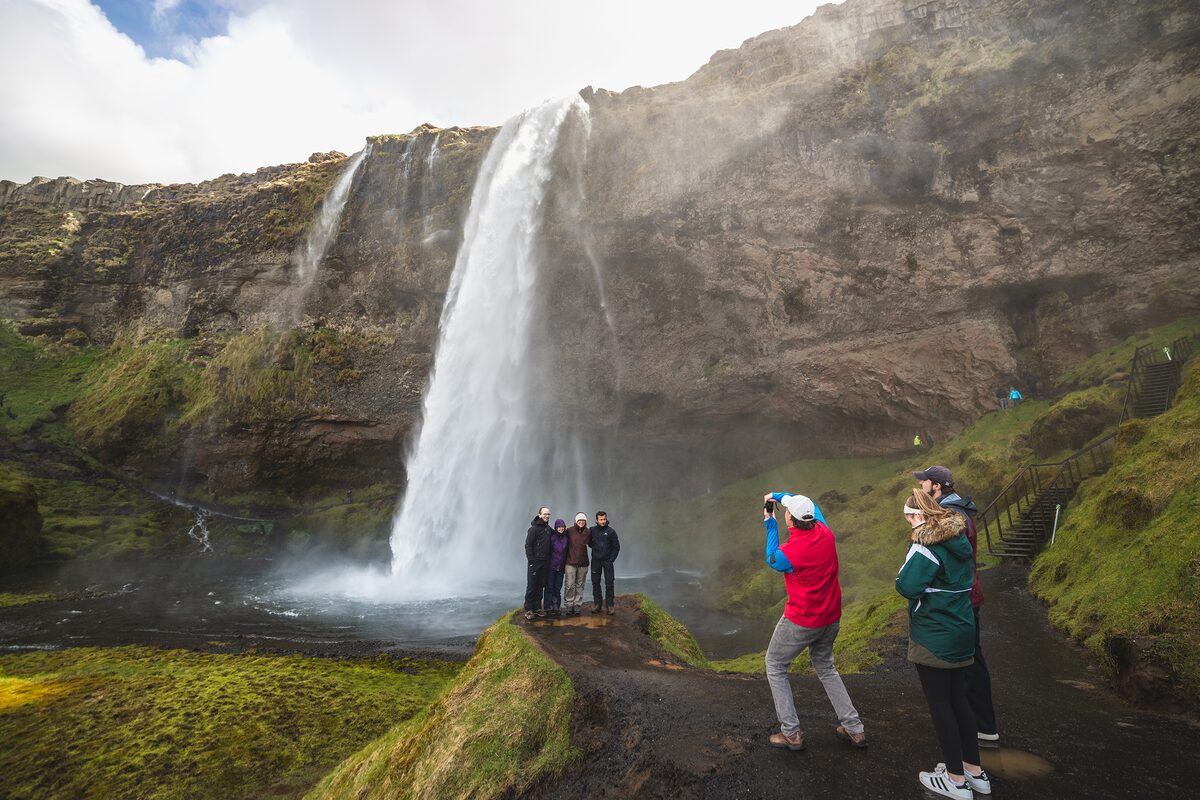 Excited tourists shooting photos by waterfall in Iceland