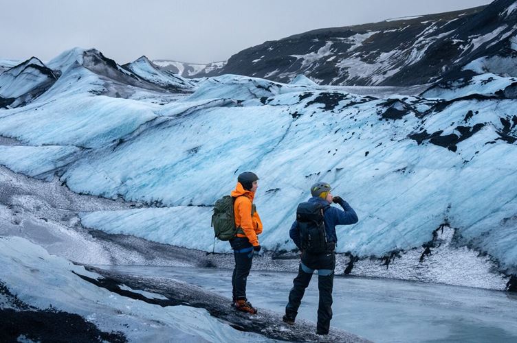 Discovering the Solheimajokull glacier Two men standing and observing Solheimajokull's ice