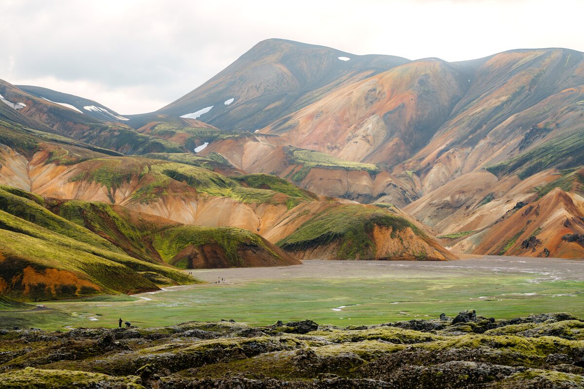 The Landmannalaugar hiking trail large field leading up to large multi colored mountain 