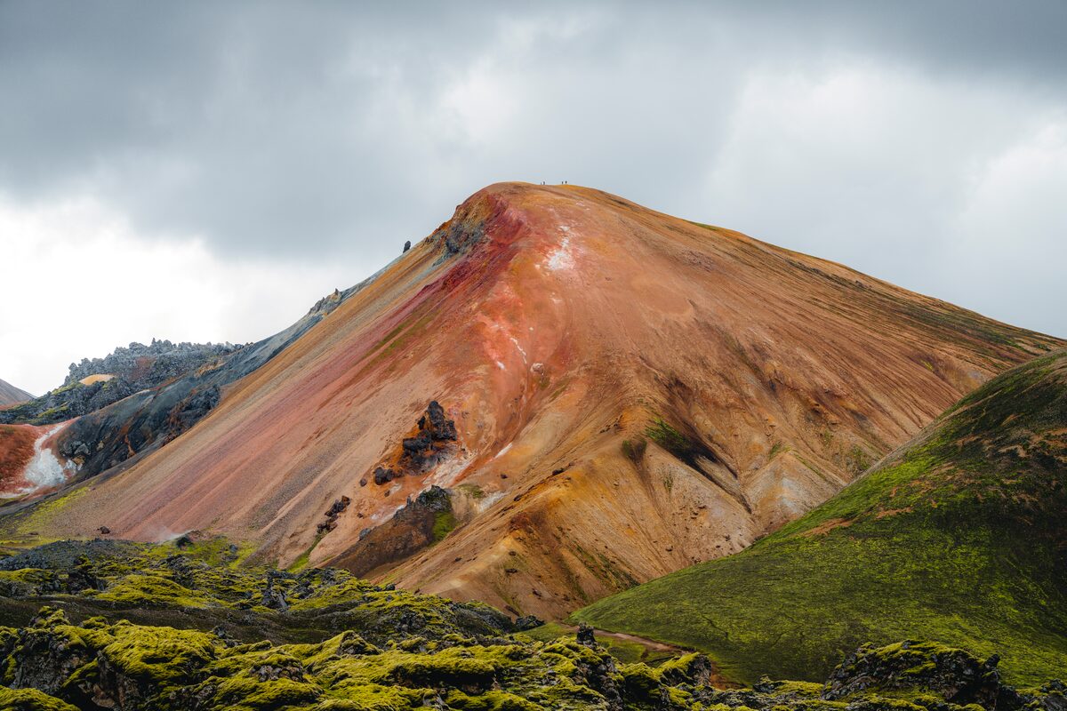 Brennisteinsalda's red and orange slopes above black lava and green moss in Landmannalaugar. 