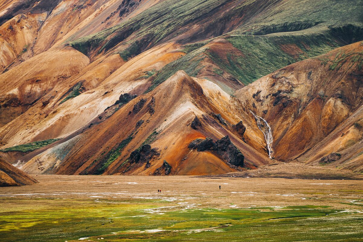 Multi colored rhyolite Landmannalaugar mountain up close with tourists walking towards