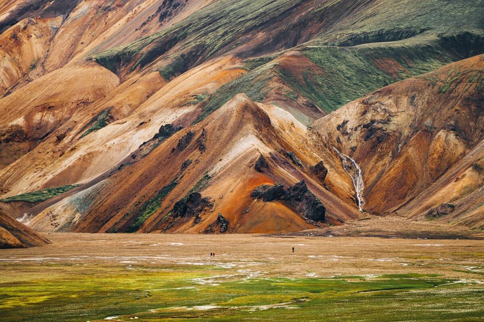 Multi colored rhyolite Landmannalaugar mountain up close with tourists walking towards
