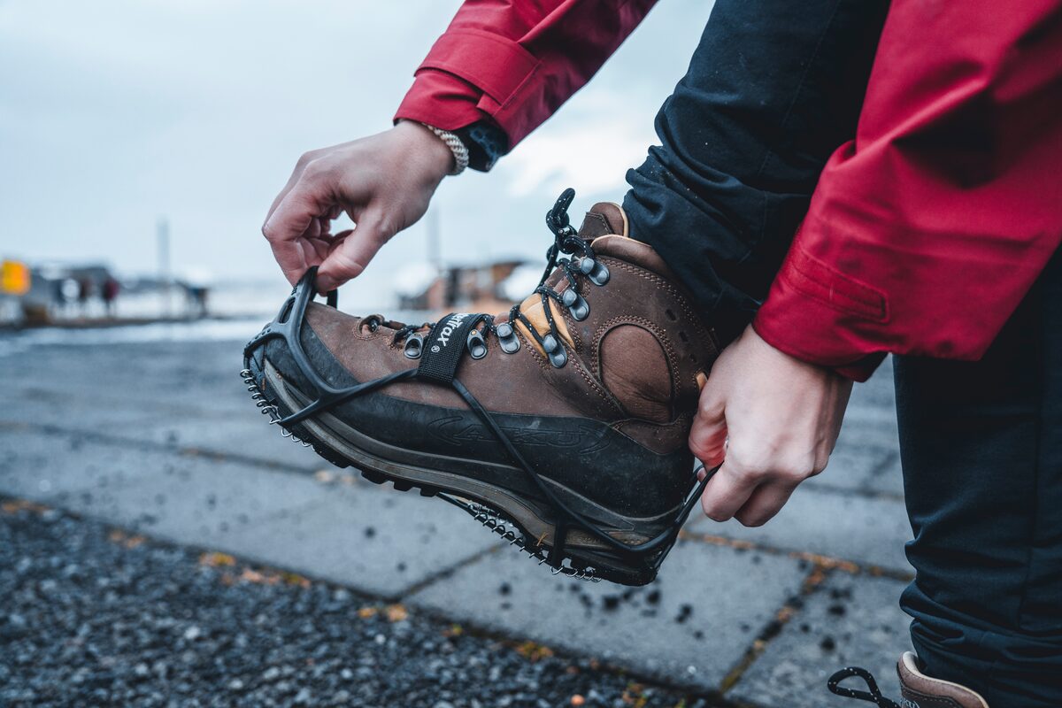Brown hiking boots with black Yaktrax ice spikes ontop for safe ice walking.