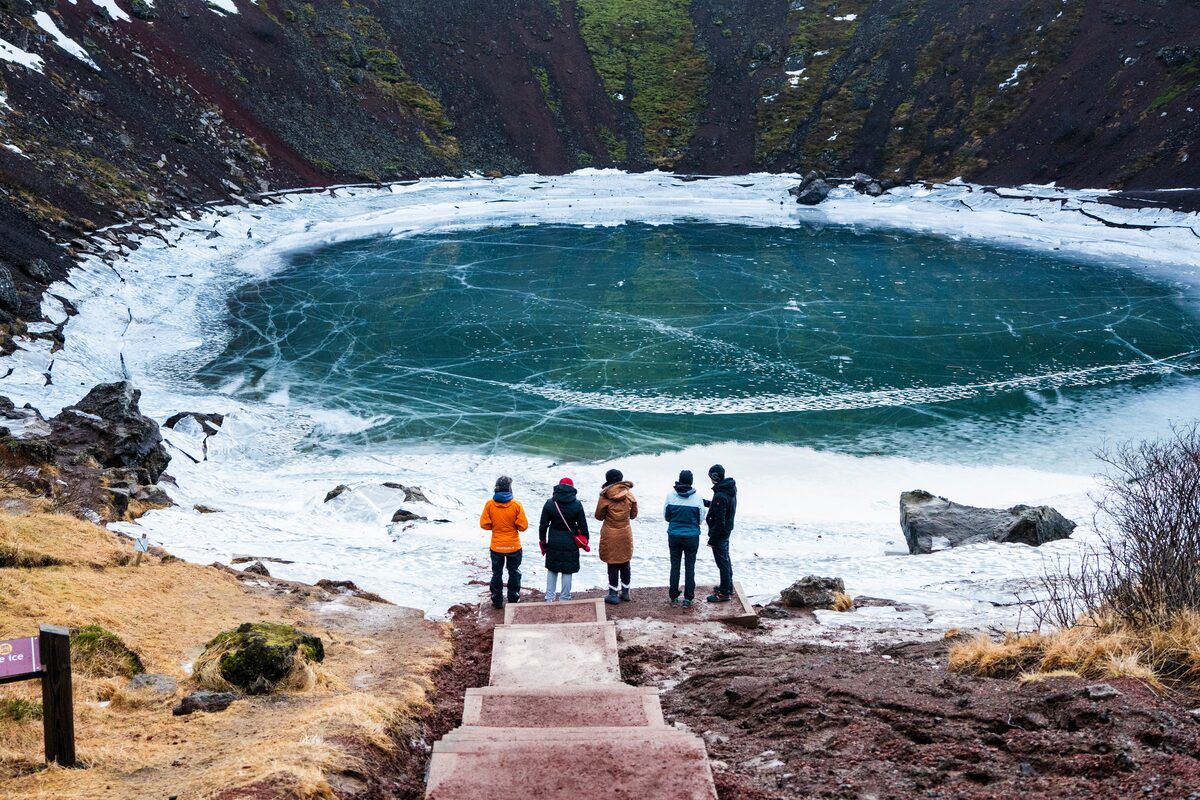 Small tourist group at bottom of steps to kerid crater lake in winter