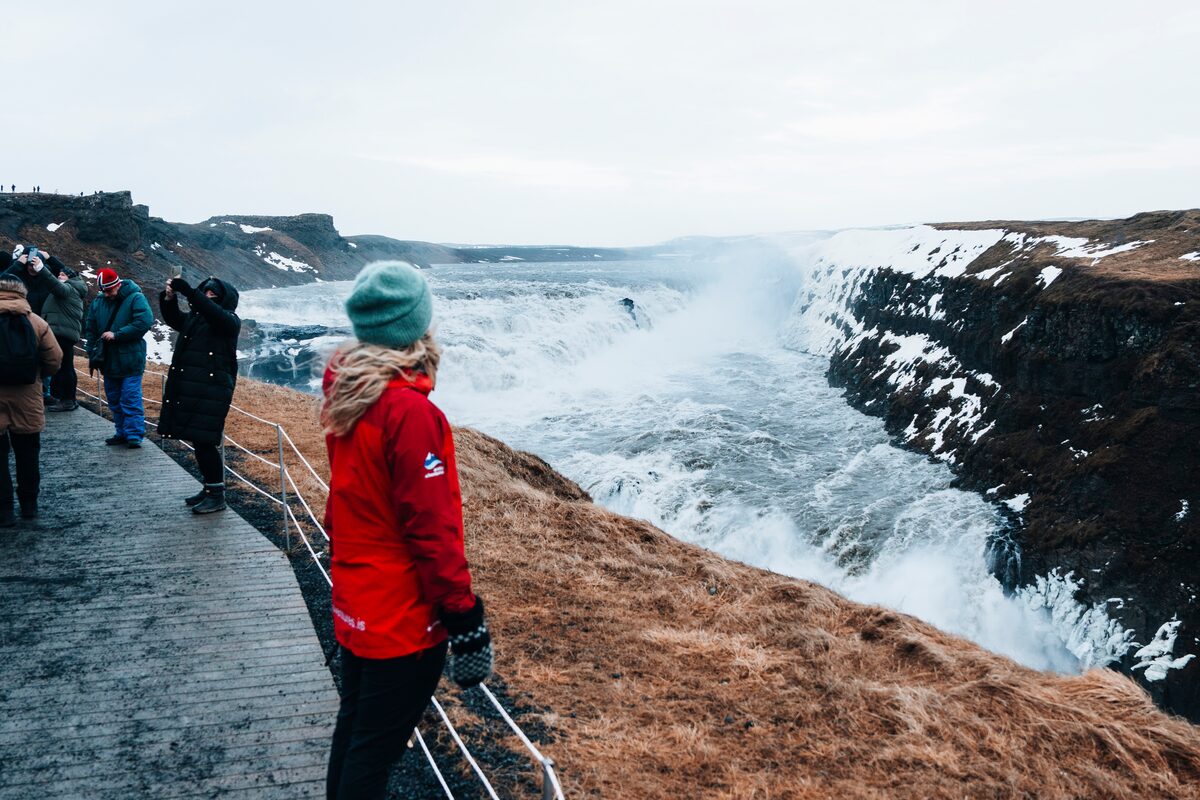 Tourist in red coat at winter standing at view point for Gullfoss falls 