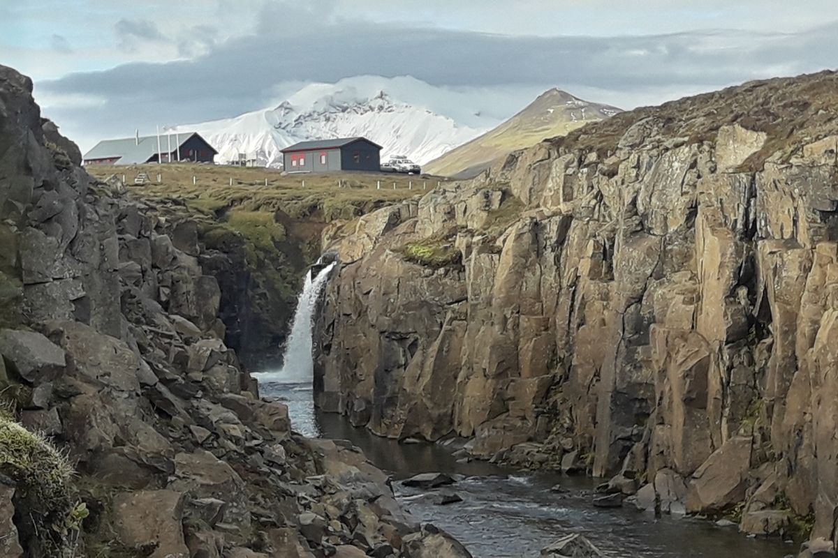 Laugarfell accomodation and hot springs above cliff and waterfall