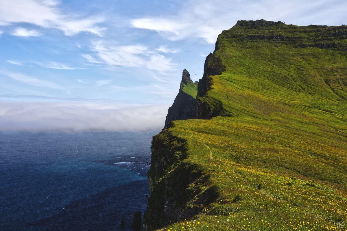 Beautiful deep blue sky and green grassy cliffside next to sea